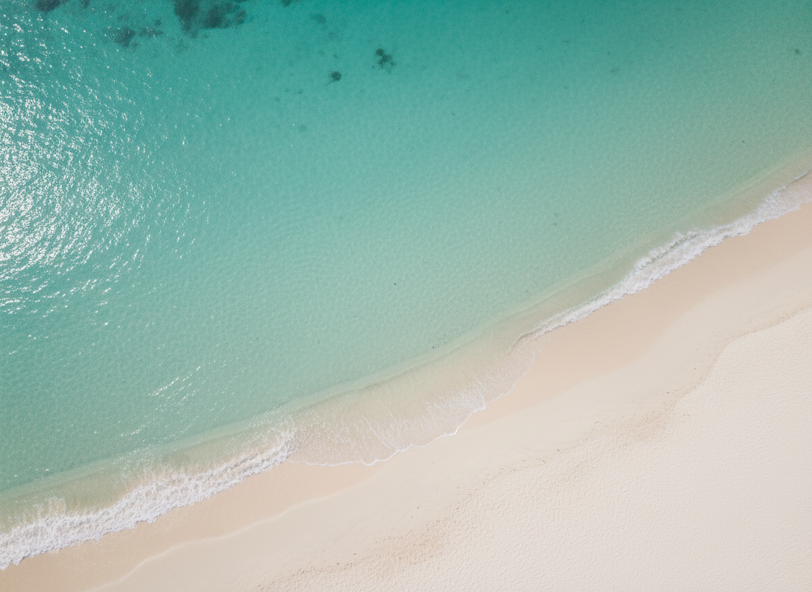 Calm turquoise ocean water meeting a pale sandy shoreline